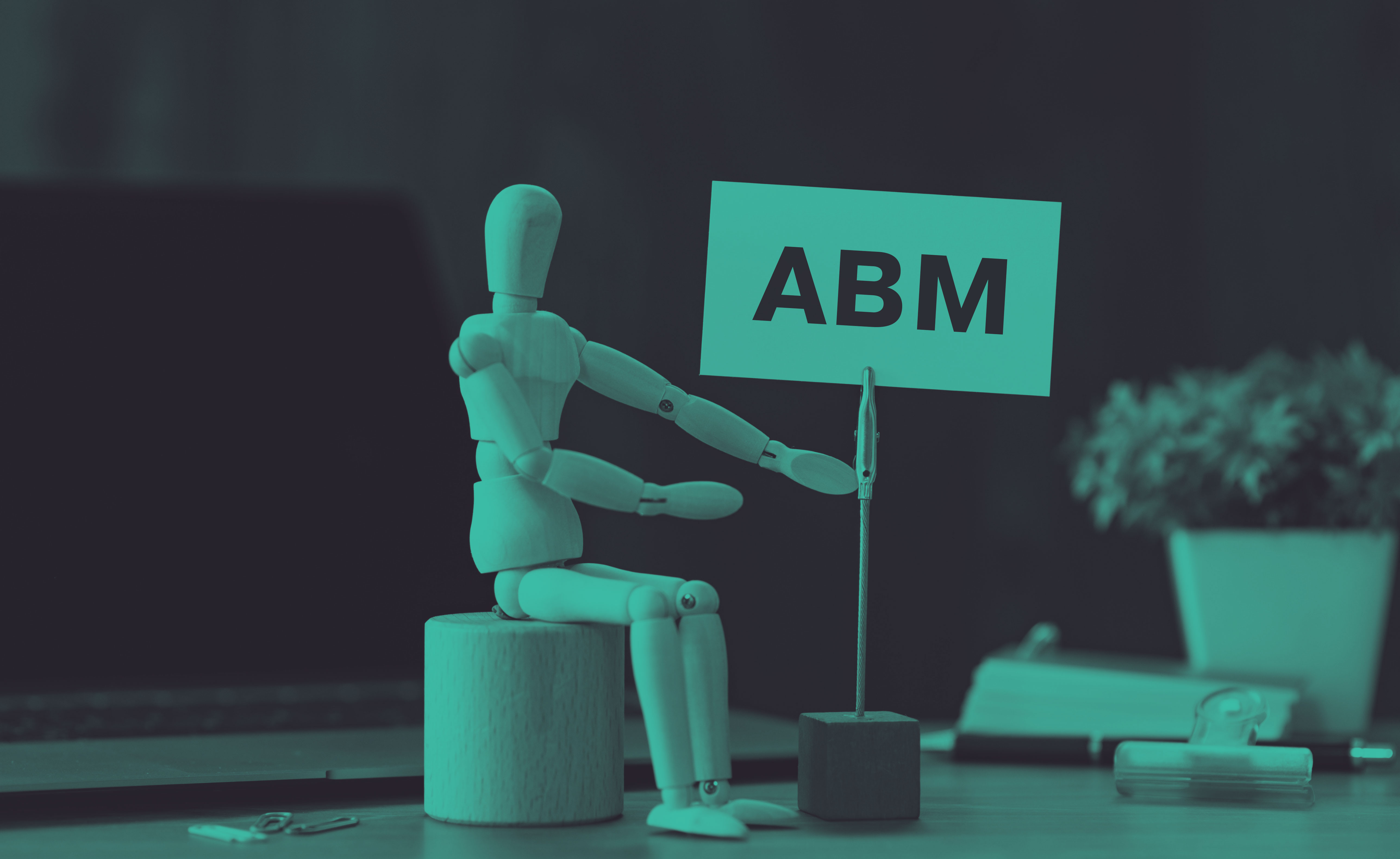 wooden figure on a desk with blocks spelling out "ABM"