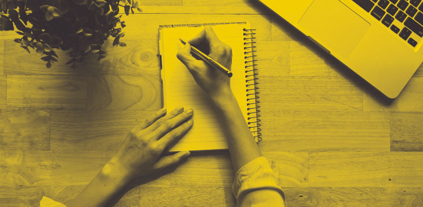 Yellow colored image form top down view of a desk and someone writing notes in a notebook