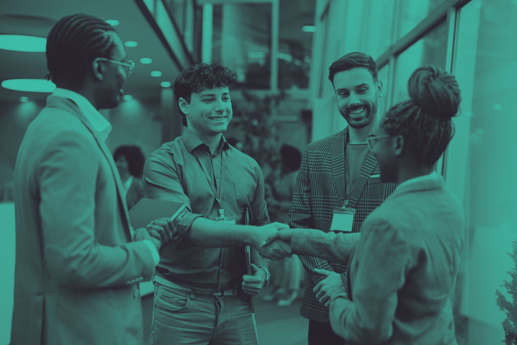 smiling group of four people at a conference shaking hands and meeting each other