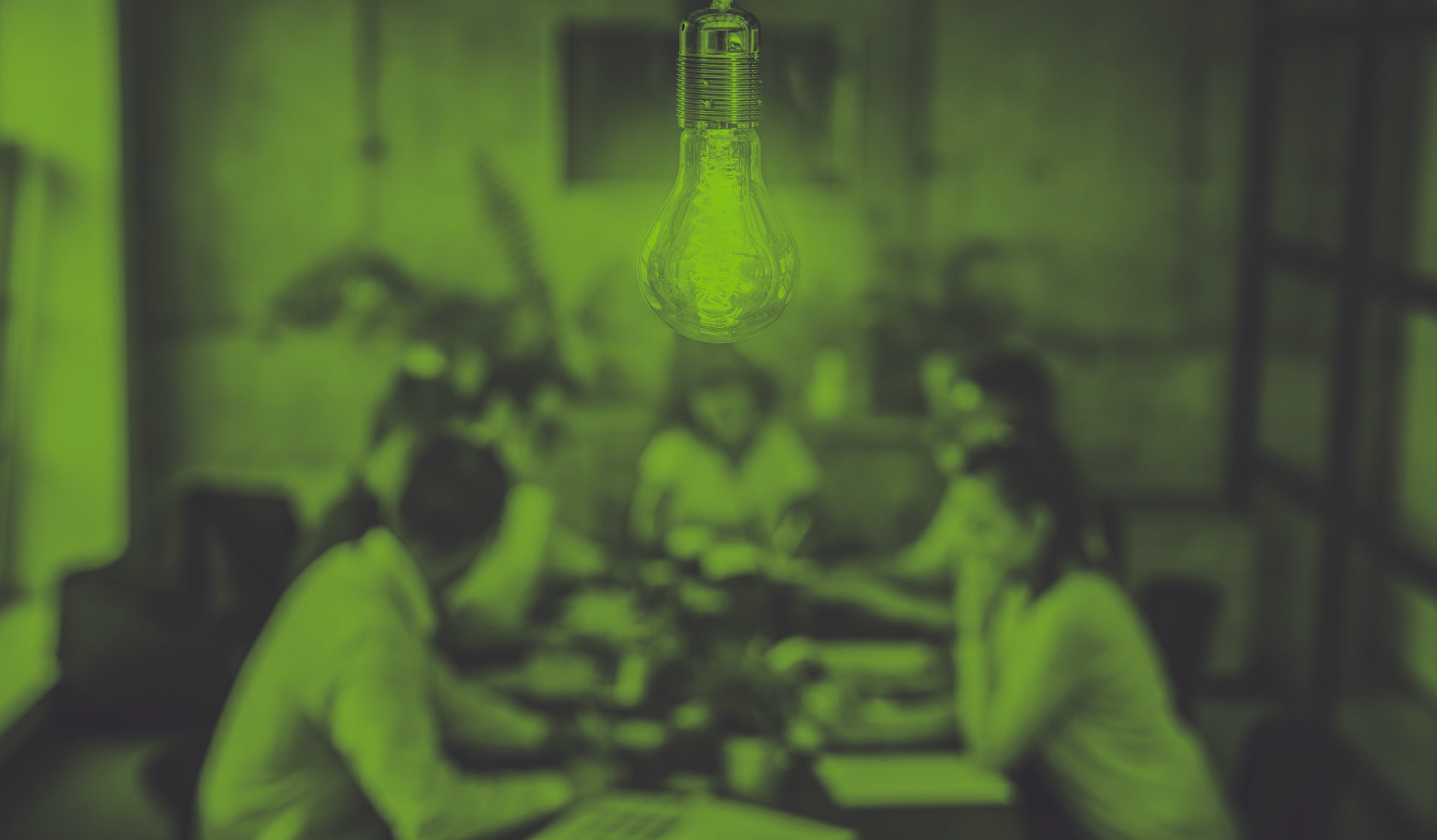 photo of lightbulb in foreground with team at a table in the background