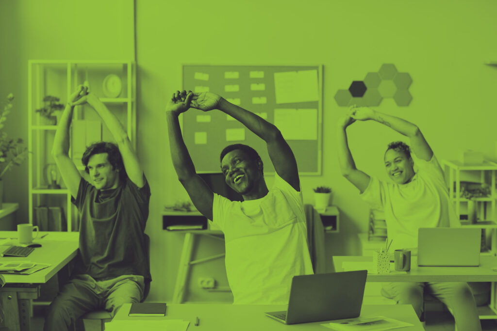 a diverse group of 3 employees stretching at their office desks