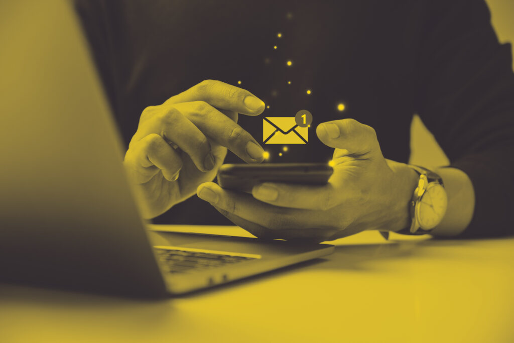a man's hands holding a phone with an email icon floating above it with sparkles